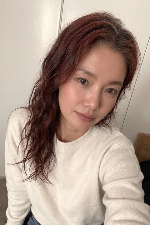 Nina taking a relaxed selfie in a cream sweater